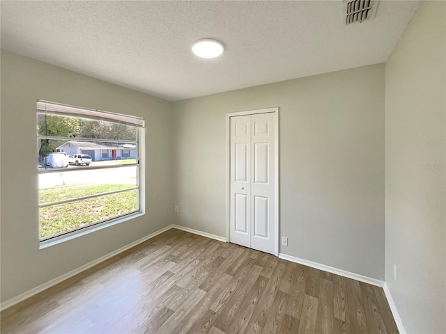 empty room with wood finished floors, a textured ceiling, and baseboards