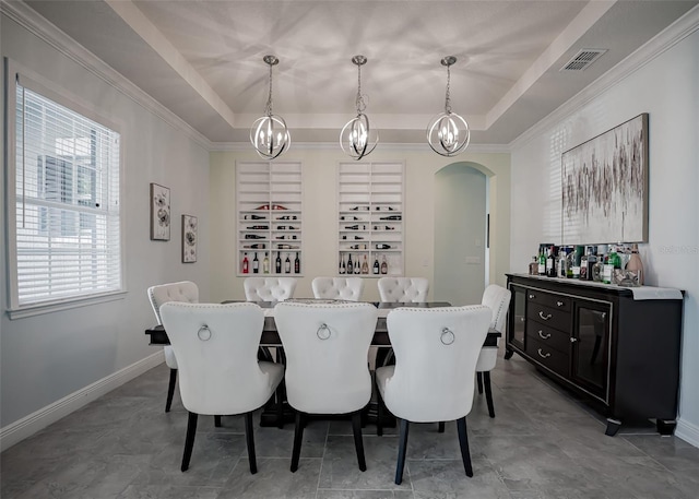 dining space with a raised ceiling, arched walkways, a chandelier, baseboards, and crown molding