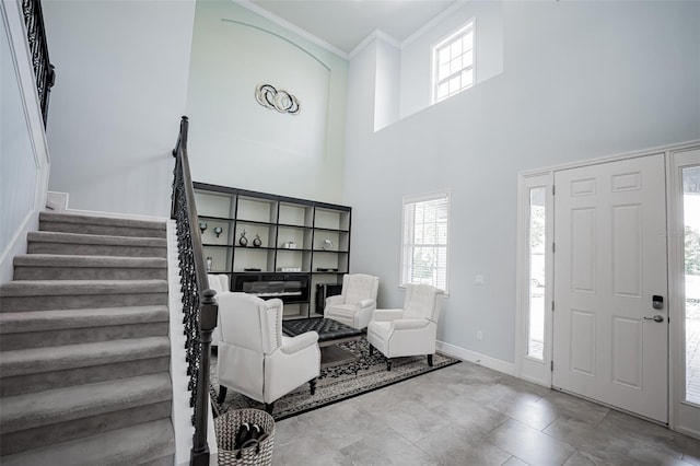 foyer with stairway, crown molding, plenty of natural light, and baseboards