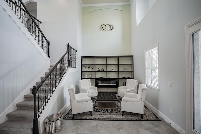 living area with a high ceiling, baseboards, stairway, concrete floors, and crown molding