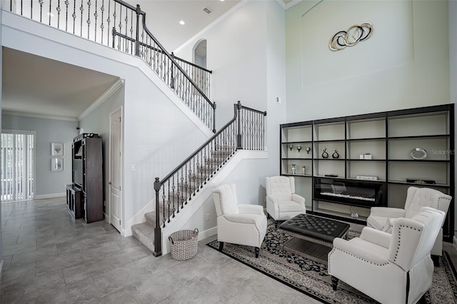 living area with crown molding, stairway, baseboards, and a towering ceiling