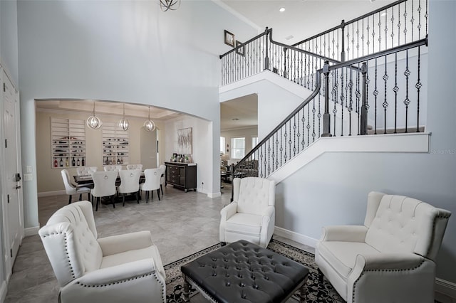 living area with a towering ceiling, stairs, baseboards, and arched walkways