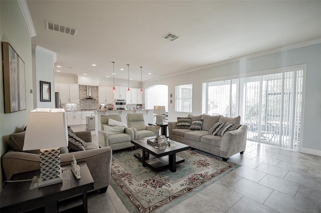 living area featuring arched walkways, ornamental molding, recessed lighting, and baseboards