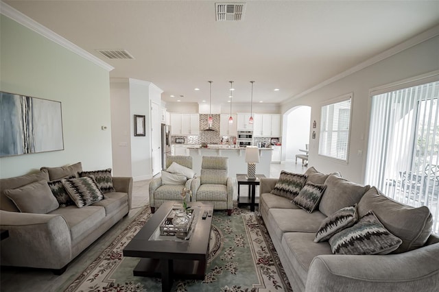 living room featuring arched walkways, ornamental molding, recessed lighting, and baseboards