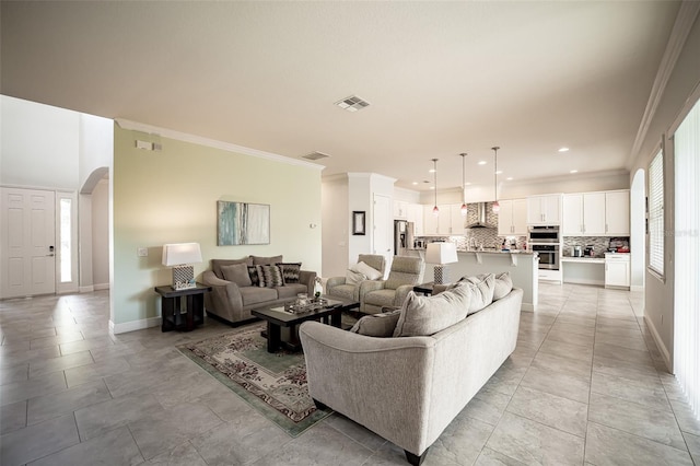 living area featuring arched walkways, ornamental molding, baseboards, and recessed lighting
