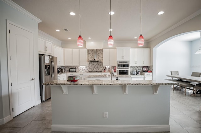 kitchen featuring stainless steel appliances, arched walkways, ornamental molding, decorative backsplash, and a kitchen bar