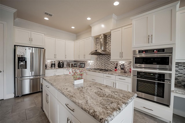 kitchen featuring appliances with stainless steel finishes, wall chimney exhaust hood, backsplash, crown molding, and white cabinetry