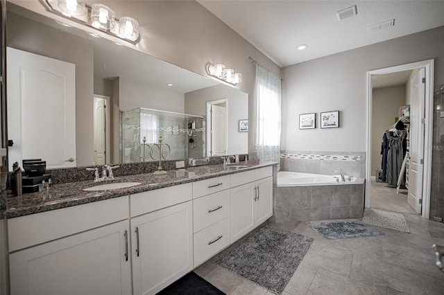 full bathroom featuring a stall shower, a bath, double vanity, and a spacious closet