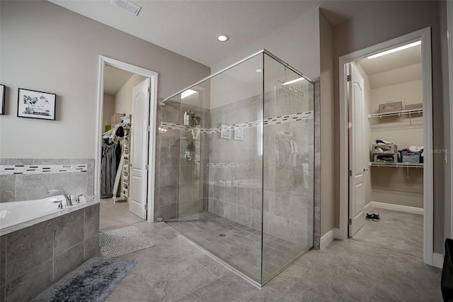 full bath with a shower stall, a bath, and a walk in closet