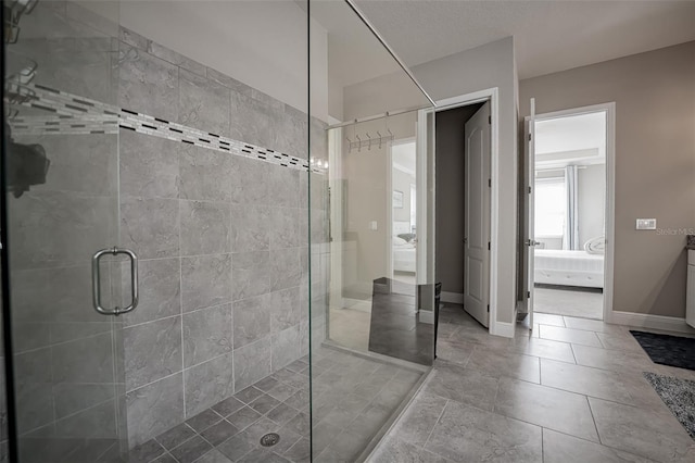 ensuite bathroom with a shower stall, baseboards, and tile patterned floors