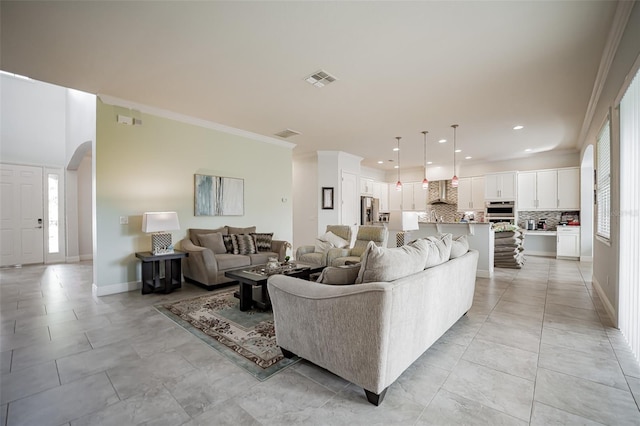 living room with ornamental molding, arched walkways, baseboards, and recessed lighting