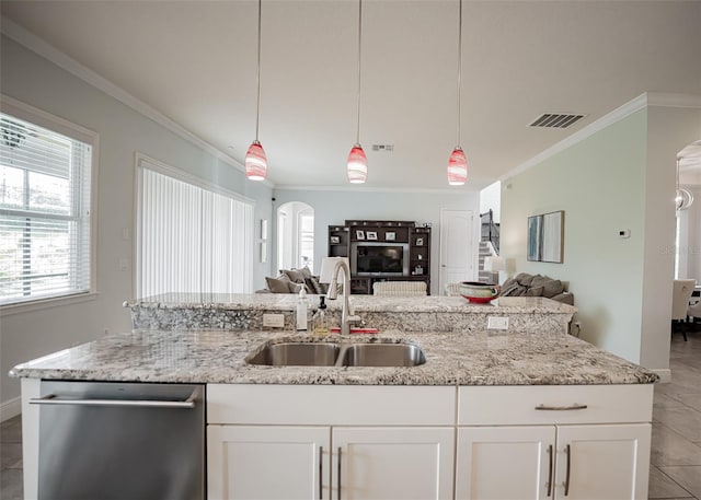 kitchen with stainless steel dishwasher, a sink, open floor plan, arched walkways, and ornamental molding