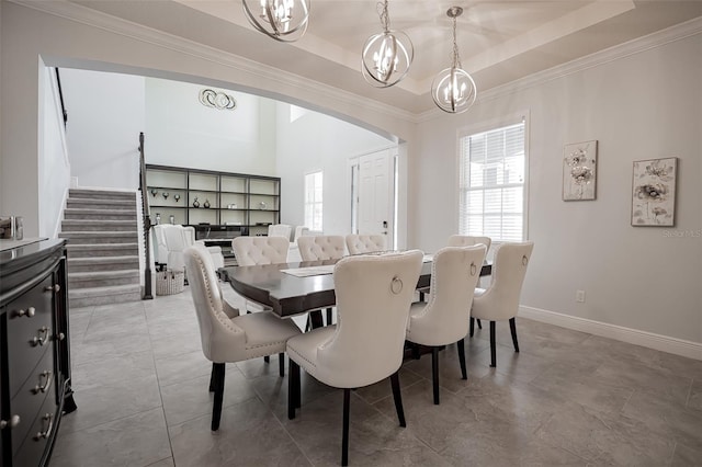 dining area featuring a chandelier, arched walkways, crown molding, baseboards, and a tray ceiling
