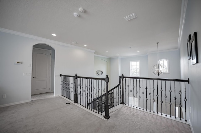 corridor featuring an upstairs landing, carpet floors, a chandelier, baseboards, and ornamental molding