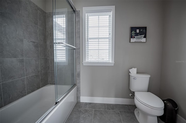 full bathroom with baseboards, toilet, plenty of natural light, and combined bath / shower with glass door