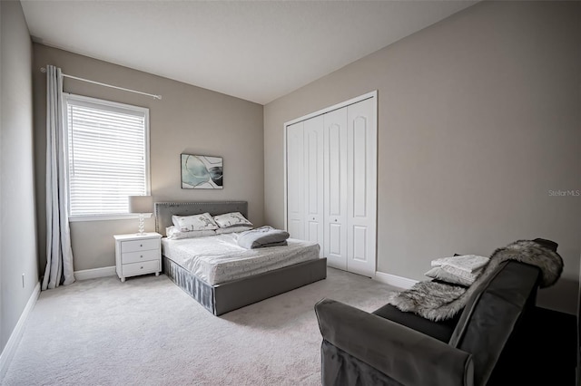 carpeted bedroom with a closet and baseboards
