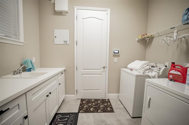 washroom featuring washing machine and clothes dryer, cabinet space, and baseboards