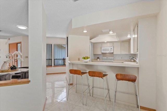 2652 Bent Hickory Cir, Longwood, FL 32779 - kitchen featuring white appliances, light countertops, decorative backsplash, a breakfast bar, and baseboards
