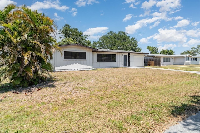single story home with board and batten siding, a garage, and a front lawn