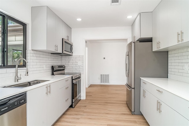 kitchen featuring appliances with stainless steel finishes, a sink, light wood-style floors, light countertops, and recessed lighting