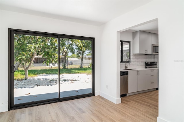 doorway to outside featuring a sink, light wood finished floors, and baseboards
