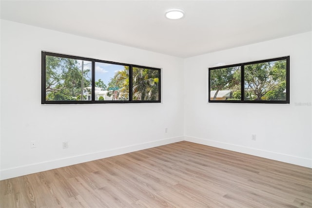 unfurnished room with plenty of natural light, baseboards, and light wood-style floors