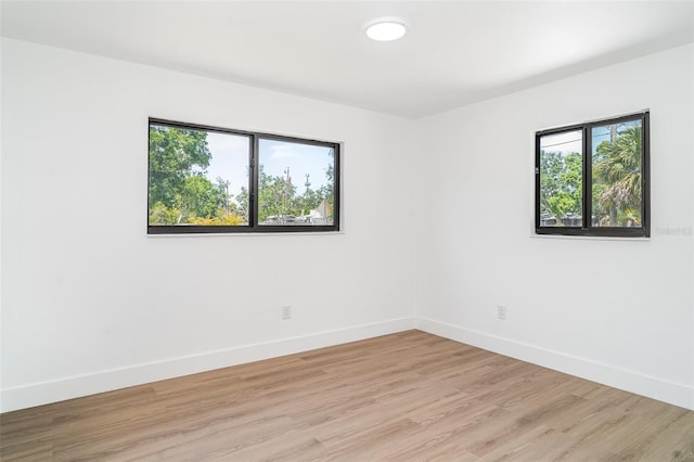 spare room with baseboards and light wood-style floors