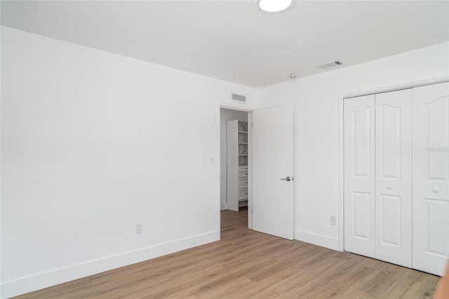 unfurnished bedroom featuring light wood-style floors, baseboards, and a closet