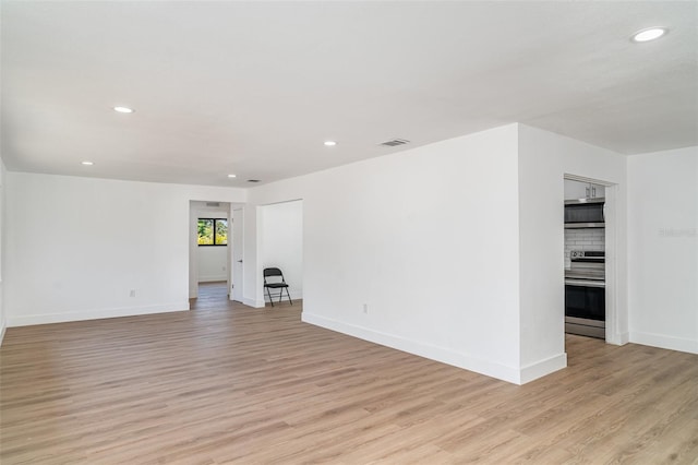 empty room featuring light wood-style floors, recessed lighting, and baseboards