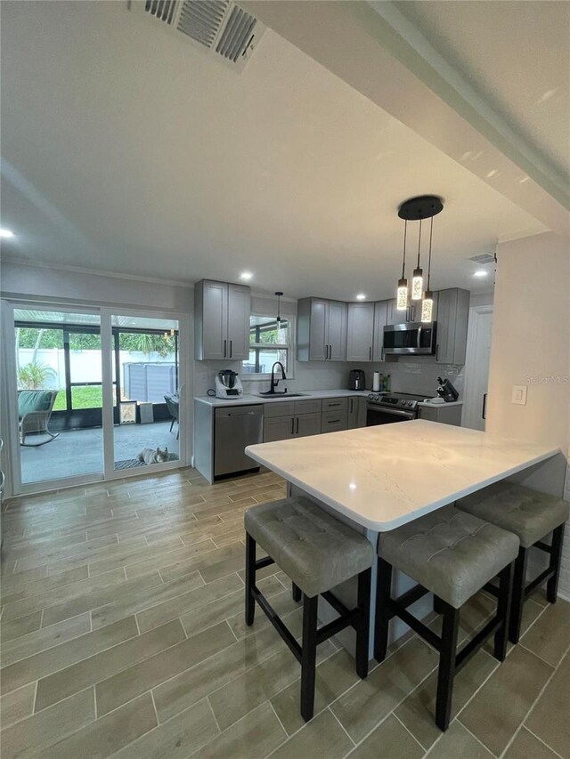 9153 86th Ave, Seminole, FL 33777 - kitchen featuring stainless steel appliances, gray cabinetry, light countertops, a sink, and a peninsula
