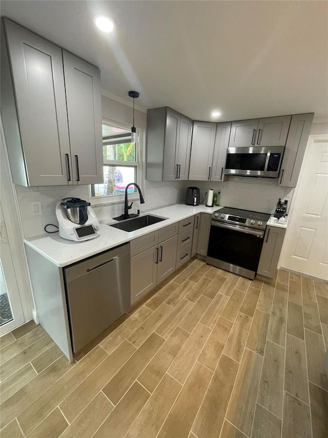 9153 86th Ave, Seminole, FL 33777 - kitchen featuring stainless steel appliances, gray cabinets, light wood-style floors, a sink, and light countertops
