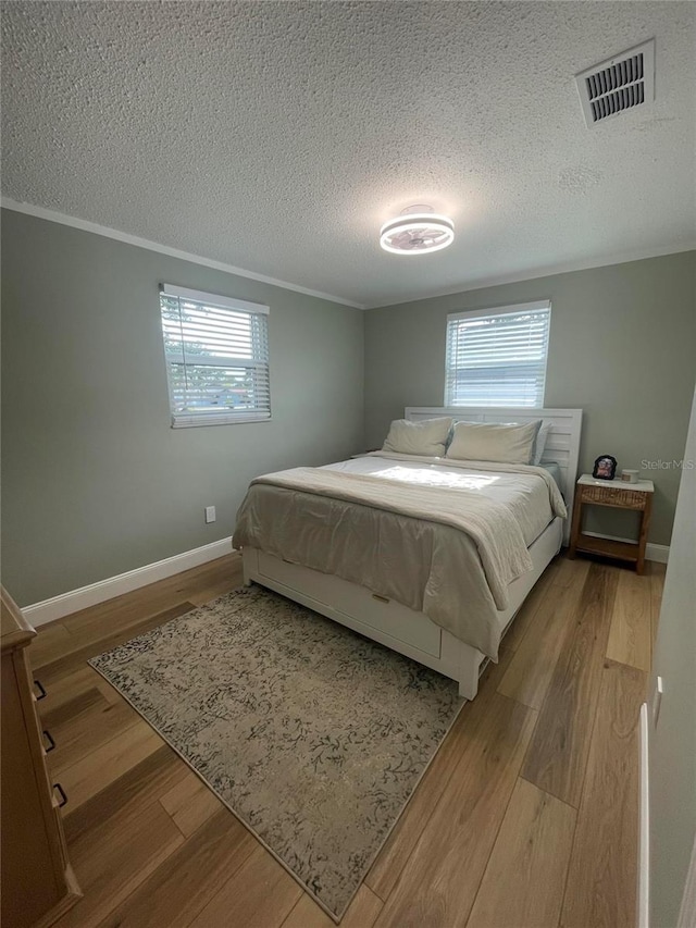 9153 86th Ave, Seminole, FL 33777 - bedroom featuring a textured ceiling, multiple windows, wood finished floors, ornamental molding, and baseboards