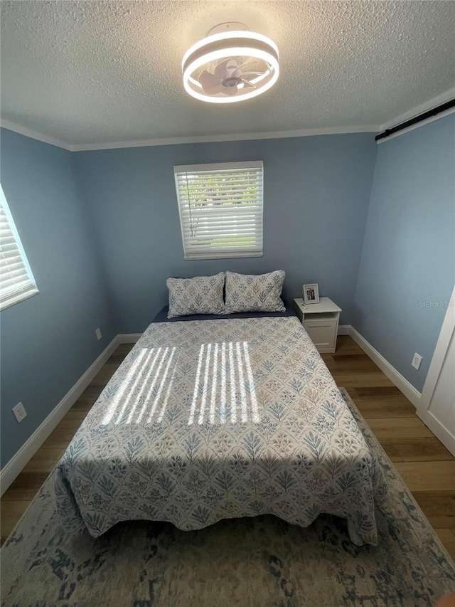 9153 86th Ave, Seminole, FL 33777 - bedroom featuring a textured ceiling, light wood-style flooring, baseboards, ornamental molding, and a barn door