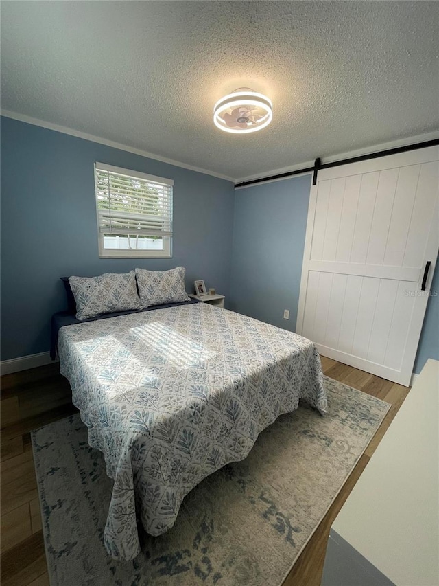 9153 86th Ave, Seminole, FL 33777 - bedroom featuring wood finished floors, a textured ceiling, crown molding, a barn door, and baseboards