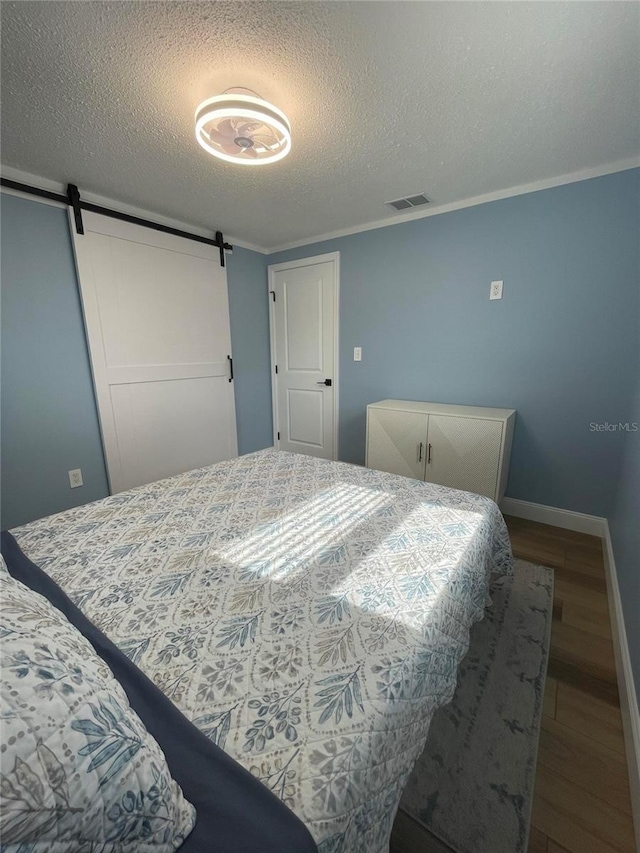 9153 86th Ave, Seminole, FL 33777 - bedroom with a barn door, a textured ceiling, wood finished floors, baseboards, and ornamental molding