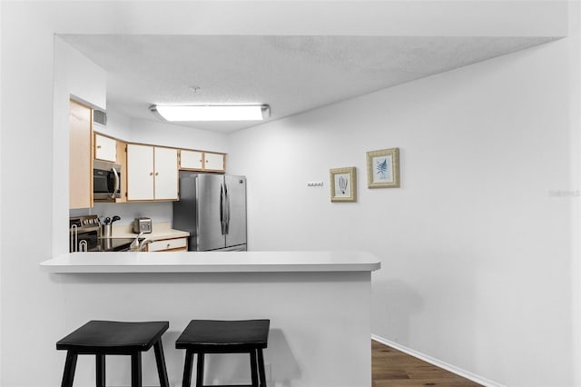3900 Southpointe Dr Unit 127, Orlando, FL 32822 - kitchen with stainless steel appliances, light countertops, a kitchen bar, dark wood-style flooring, and a peninsula