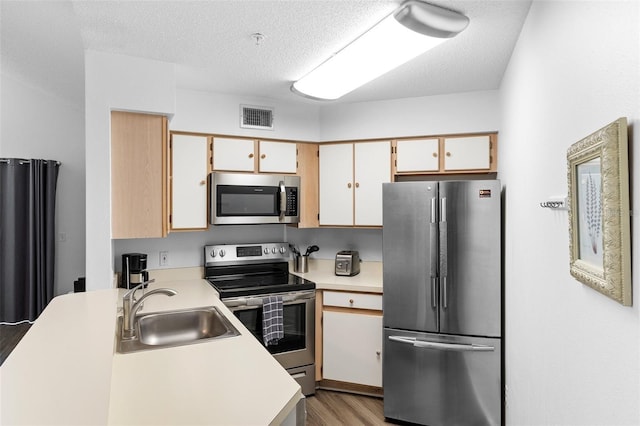 3900 Southpointe Dr Unit 127, Orlando, FL 32822 - kitchen with stainless steel appliances, a sink, light countertops, light wood-style floors, and a textured ceiling