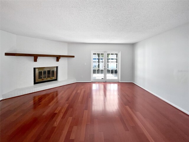 6623 Baybrooks Cir, Temple Terrace, FL 33617 - unfurnished living room with a textured ceiling, wood finished floors, a fireplace, french doors, and baseboards