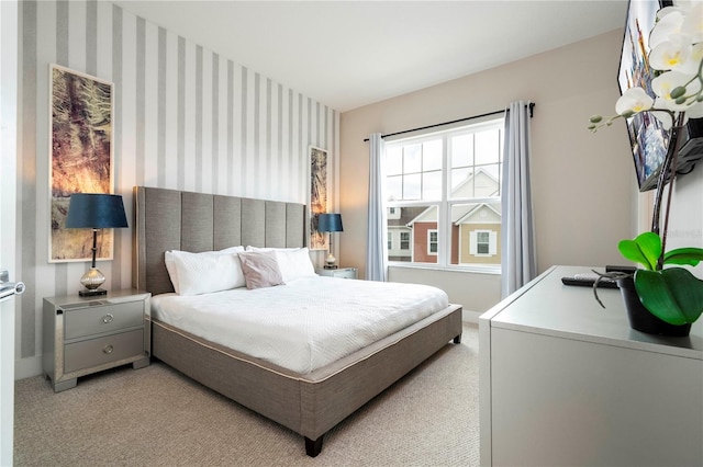 bedroom featuring light carpet, wallpapered walls, and baseboards