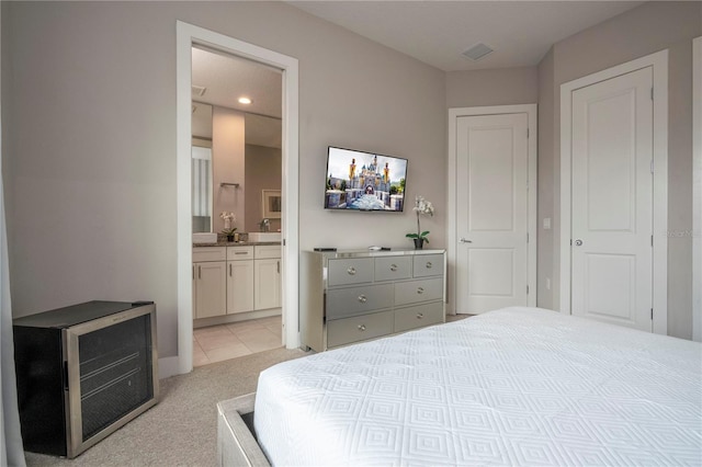 bedroom featuring light carpet, baseboards, recessed lighting, ensuite bath, and light tile patterned floors