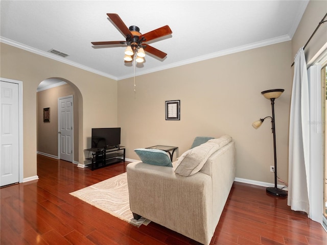 living area featuring ceiling fan, arched walkways, wood finished floors, crown molding, and baseboards