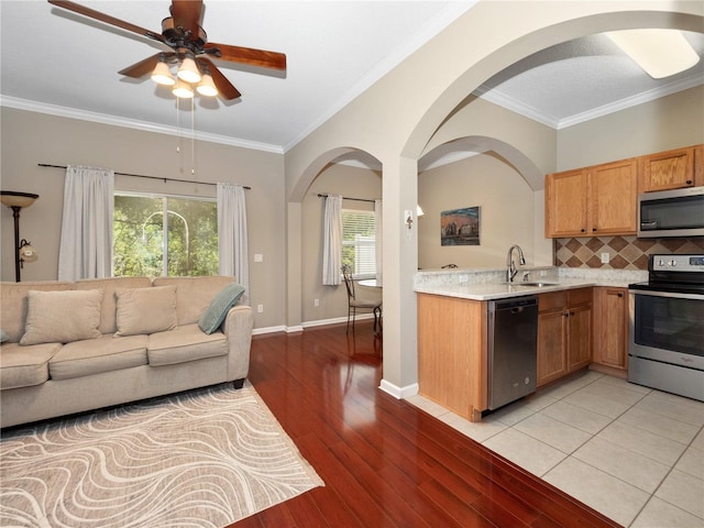 kitchen featuring appliances with stainless steel finishes, a sink, light countertops, open floor plan, and light wood finished floors