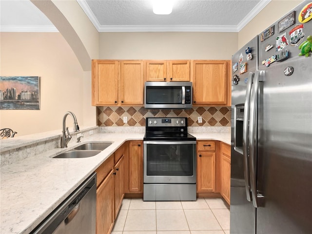kitchen with stainless steel appliances, a sink, ornamental molding, tasteful backsplash, and arched walkways