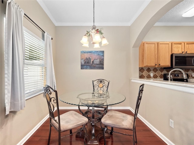 dining space with dark wood-style floors, arched walkways, baseboards, a chandelier, and crown molding