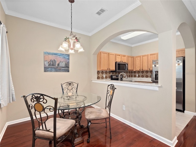 dining space with arched walkways, dark wood-style flooring, a chandelier, and crown molding