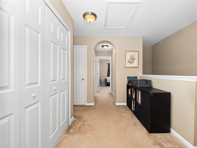 corridor featuring light colored carpet, arched walkways, and baseboards