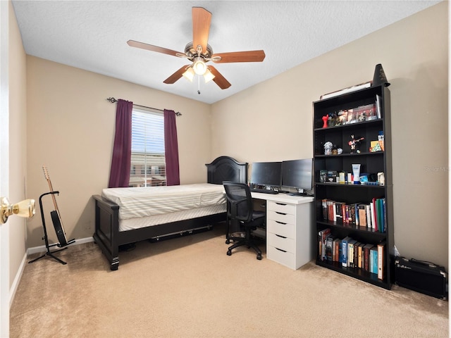 carpeted bedroom featuring a ceiling fan, an office area, and baseboards