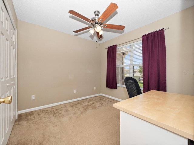 office space featuring light carpet, a ceiling fan, and baseboards