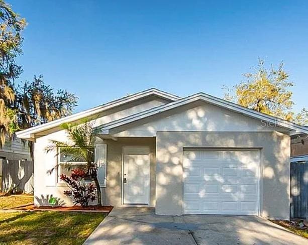 single story home with stucco siding, a garage, and concrete driveway