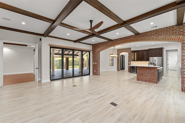 1741 Palmer Ave, Winter Park, FL 32789 - unfurnished living room featuring arched walkways, baseboards, ceiling fan, beamed ceiling, and light wood-style floors